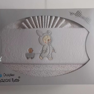 Conjunto de fraldas bordadas com criança em fato de coelho e estampado de estrelas em embalagem riscada