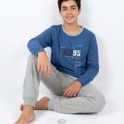 Jovem sentado no chão a usar pijama azul e cinzento, com papel à sua frente.