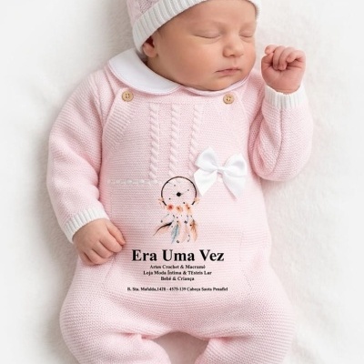 Bebé vestido com macacão e gorro rosa em malha a dormir numa superfície branca