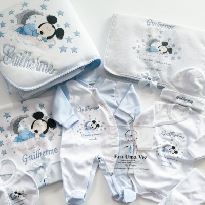 Conjunto de roupa e acessórios de bebé com personagem Mickey Mouse a dormir, em branco e azul claro.