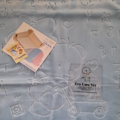 Cobertor azul com relevo de letras e desenhos infantis