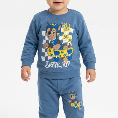 Criança com pijama azul com desenho de cão skatista e texto