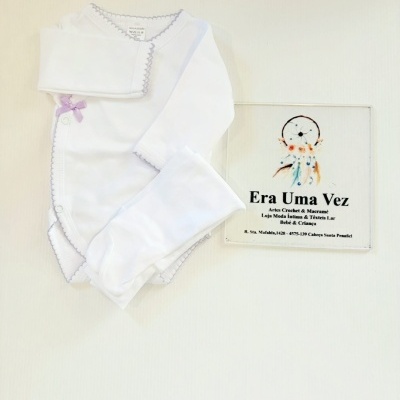 Conjunto branco para bebé com bordado lilás e lacinho lilás pequeno, placa com texto promocional