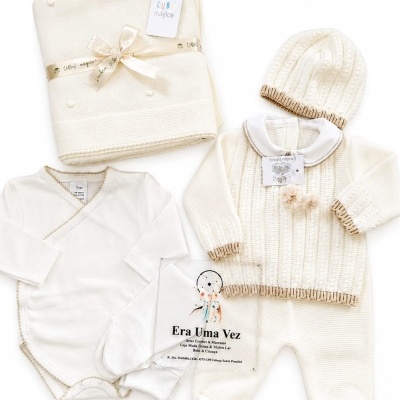 Conjunto de roupa de bebé creme com manta, gorro e body.