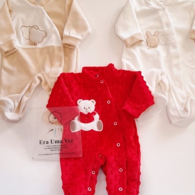 Três macacões de bebé em tons bege, branco e vermelho com aplicações de ursinho e coelhinho e botões na frente