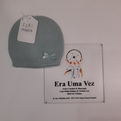 Gorro tricotado azul claro com etiqueta e placa promocional ao lado