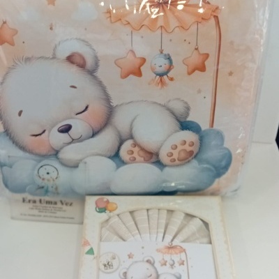 Ilustração de urso dormindo sobre nuvens com estrelas, em embalagem infantil colorida