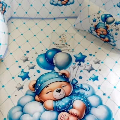 Roupa de cama de bebé com padrão de ursinho azul em nuvens e balões.
