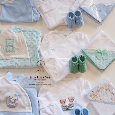 Conjunto de roupa de bebé em azul, verde e branco com bordados de ursinhos sobre fundo branco.