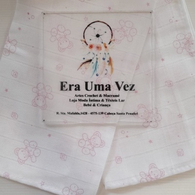 Toalha branca com padrão rosa e rótulo com nome e endereço da loja
