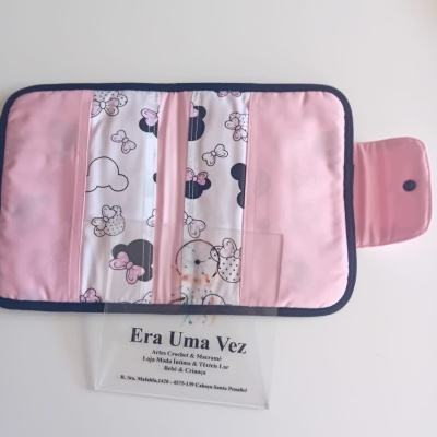 Carteira cor-de-rosa com padrão de laços e silhuetas, junto de cartão de visita transparente com texto