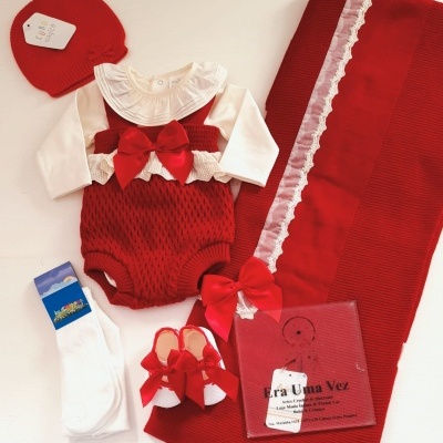 Conjunto de roupa de bebé vermelha com acessórios e embalagem em fundo branco