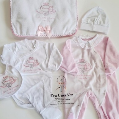 Conjunto de roupa de bebé branco e rosa com bordados e laço cor-de-rosa, incluindo macacão, body, gorro e manta