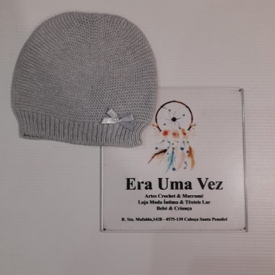 Gorro cinzento de malha com fita prateada ao lado de placa com texto e imagem de apanhador de sonhos