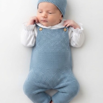 Bebé com macacão azul e gorro de malha