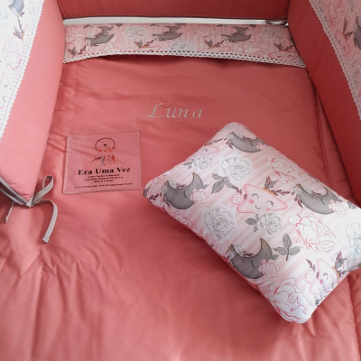 Berço cor de rosa com proteção acolchoada e almofada estampada de luas e estrelas sorridentes