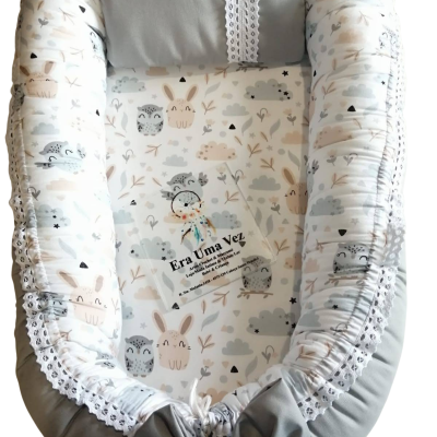 Ninho de bebé com padrão de corujas e coelhos em tons neutros.