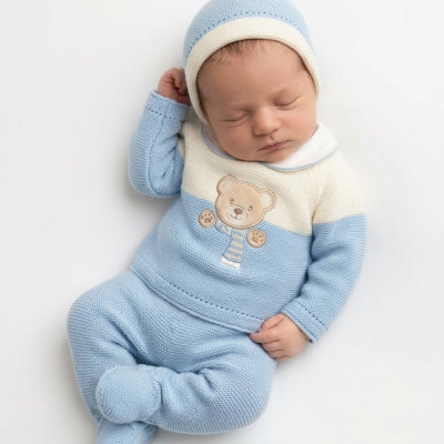 Bebé a dormir vestido com conjunto de roupa de lã azul e creme com ursinho bordado.