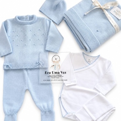 Conjunto de bebé azul claro de malha com casaco, calças, gorro, manta e body branco.