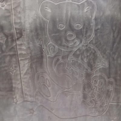 Manta cinza com desenhos em relevo de um urso e estrelas.