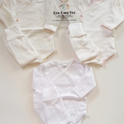 Conjuntos de roupa de bebé em algodão branco com bodies e calças, bordados em bege e rosa nas bordas.