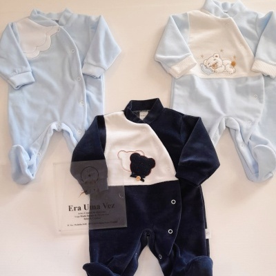 Três babygrows azul claro e azul escuro com aplicações de ursinhos e botões sobre fundo branco.