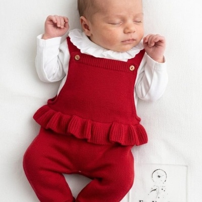 Bebé deitado com roupa vermelha e branca, ao lado uma placa com texto Era Uma Vez