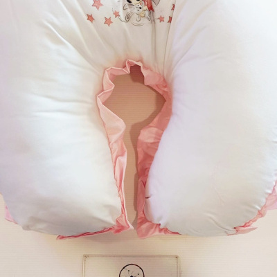 Almofada de amamentação branca e rosa com estampa da Minnie e placa informativa abaixo.