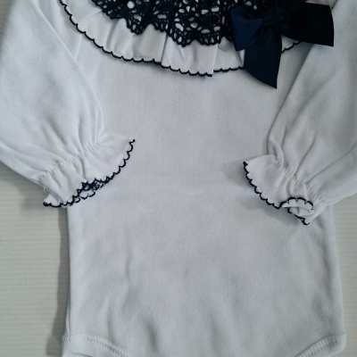 Body de bebé branco com gola e punhos com renda preta e laço preto.