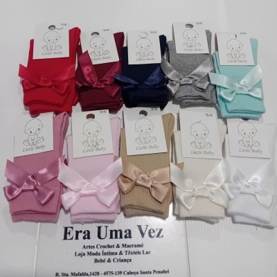 Meias de bebé coloridas com laços de cetim e etiquetas 'Little Baby' em exposição