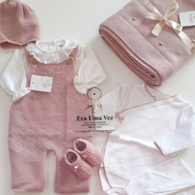 Conjunto de roupa e acessórios para bebé em rosa e branco, com textura de malha e algodão, sobre fundo branco.
