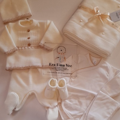 Conjunto de roupa de bebé em malha branca com detalhes bege e manta