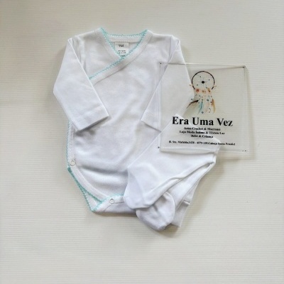 Body branco de bebé com acabamento azul claro e meias, em fundo branco, com placa transparente com texto