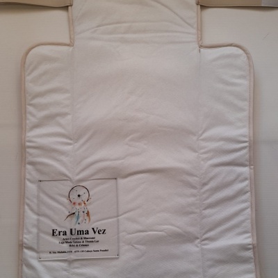 Trocador branco acolchoado com bordas bege e etiqueta com texto sobre loja artesanal.