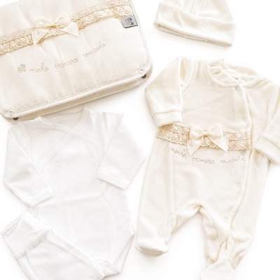 Conjunto de roupa de bebé creme e branca com laço, macacão, body, calças, gorro e capa bordada