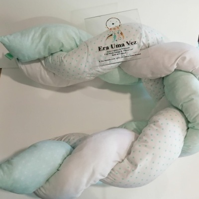 Almofada trançada em branco e verde-água com pequenas estrelas e etiqueta informativa