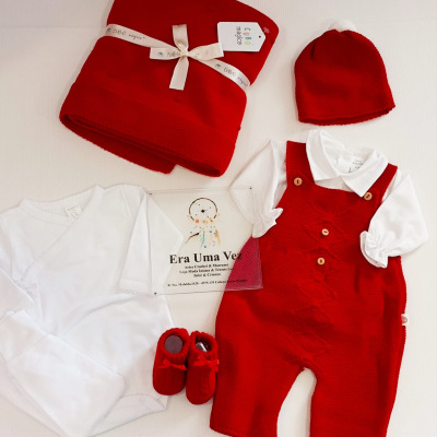 Conjunto de bebé branco e vermelho com body, macacão, gorro, sapatinhos e manta com etiqueta CUBO mágico.