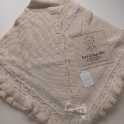 Manta de malha bege com laço branco em fundo branco