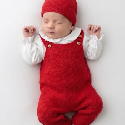 Bebé a dormir com roupa vermelha e branca sobre fundo branco