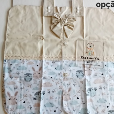 Organizador bege claro e estampado com padrão de coelhos e corujas e laço no topo