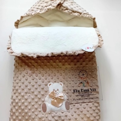 Cobertor de bebé bege com textura de bolinhas e ursinho bordado com laço