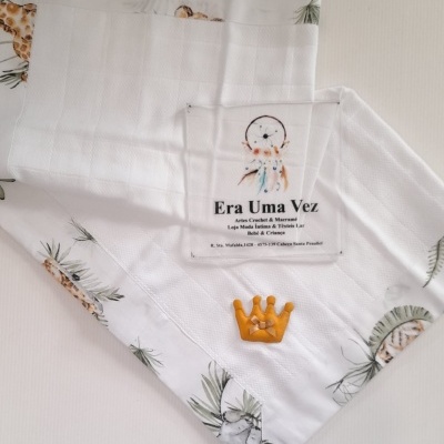 Toalha branca com padrão de folhas e animais, etiqueta com texto Era Uma Vez e bordado de coroa amarela