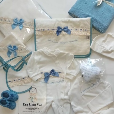 Conjunto de roupa de bebé branca com detalhes azuis e manta azul