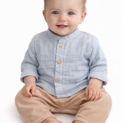Bebé sorridente com camisa azul clara e calças bege sentado