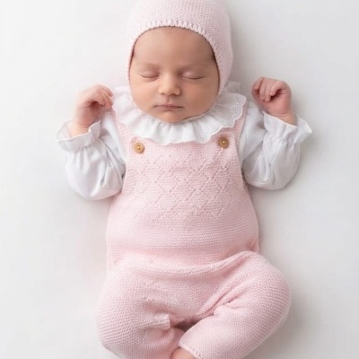 Bebé a dormir com roupa rosa e branca em fundo branco