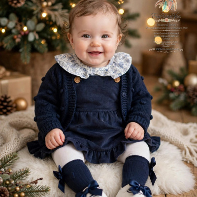 Bebé com vestido azul escuro em ambiente natalício