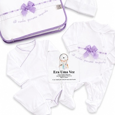 Conjunto de roupa de bebé branco com detalhes lilás e texto bordado.
