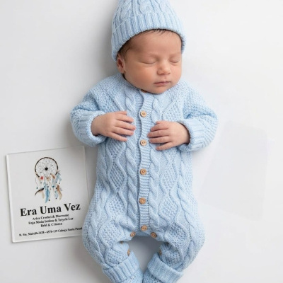Bebé dormindo com fato de malha azul claro e gorro com pompom