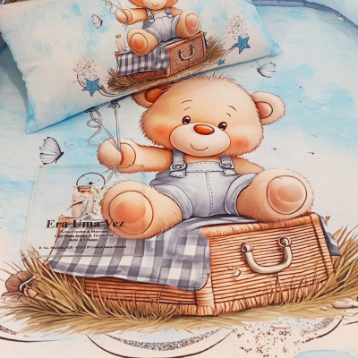 Roupa de cama infantil azul claro com estampa de ursinho sentado numa mala de vime