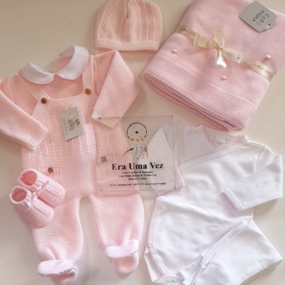 Conjunto de roupa de bebé em rosa e branco com mantinha e sapatinhos.